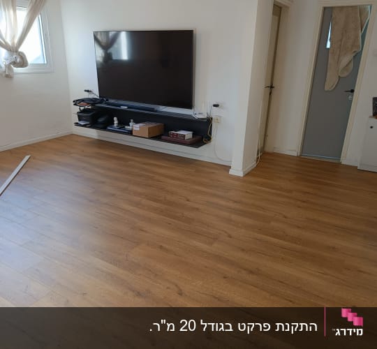 רצפת פרקט עץ בחדר עם טלוויזיה על הקיר